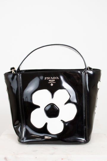 Black Prada handbag with a white flower design on a white background