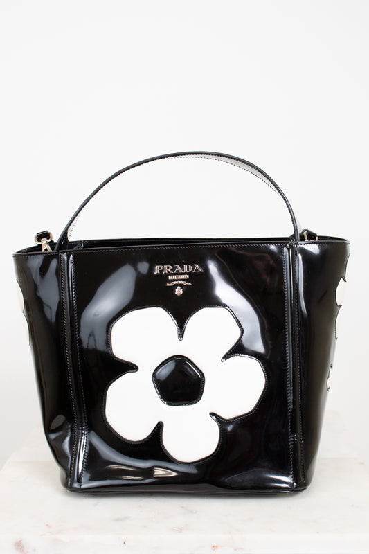 Black Prada handbag with a white flower design on a white background