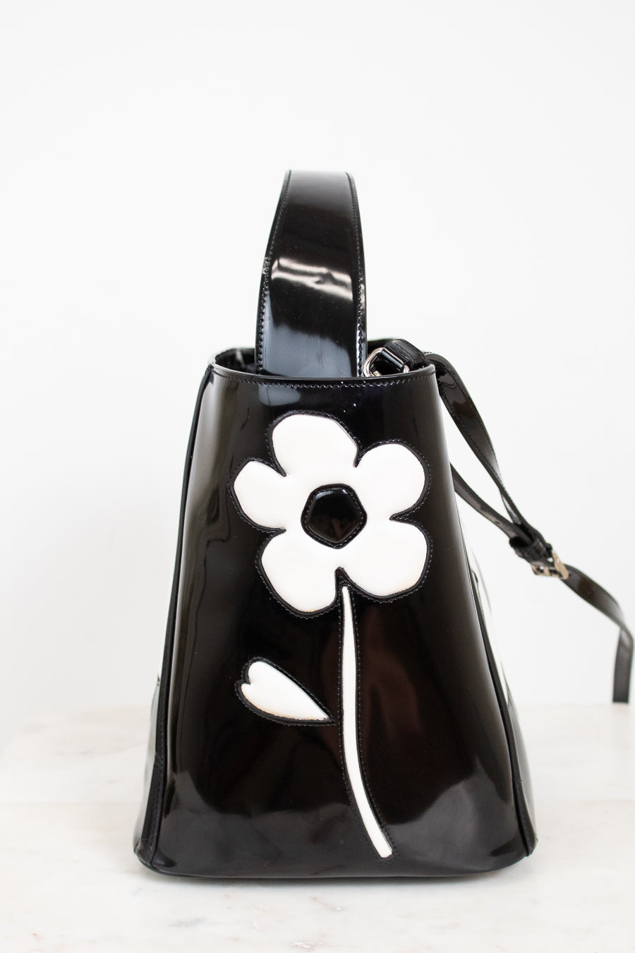 Black handbag with a white flower design on a white background