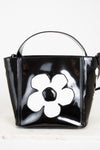 Black handbag with a white flower design on a light background
