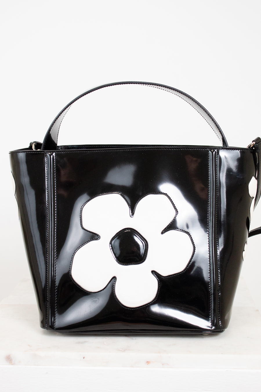 Black handbag with a white flower design on a light background