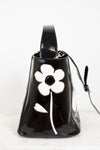 Black handbag with a white flower design on a white background