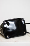 Black glossy handbag with silver studs on a light background