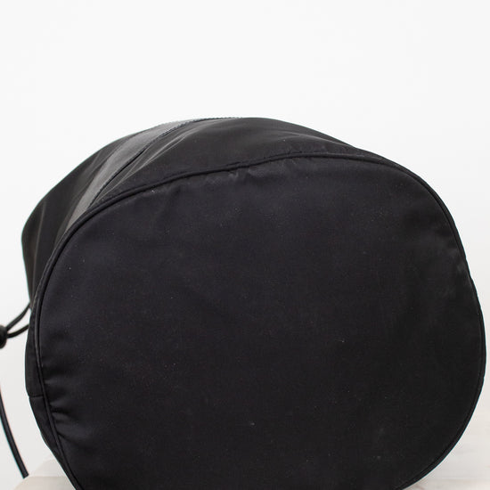 Bottom view of black nylon drawstring bucket bag displayed against a plain background