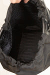 Interior of black nylon drawstring bucket bag showing printed lining and against a plain background