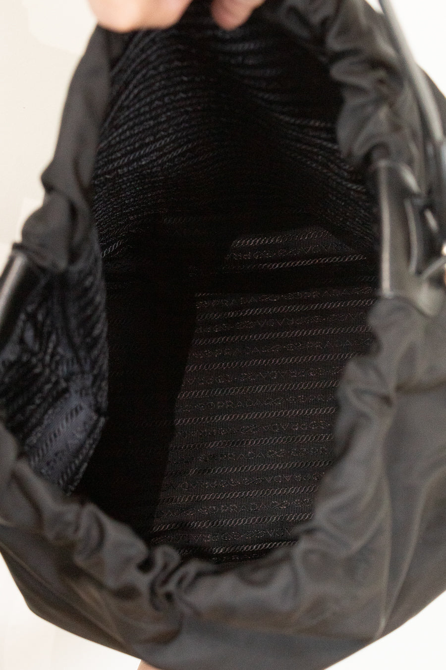 Interior of black nylon drawstring bucket bag showing printed lining and against a plain background