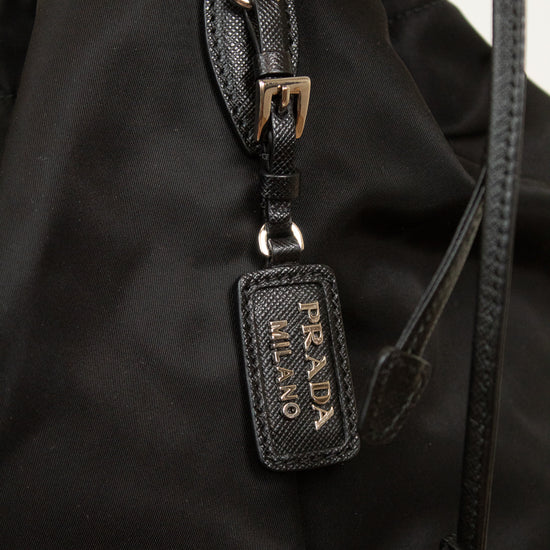 Close-up of 'Prada Milano' tag showing black leather and silver-tone details