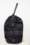 Side view of black nylon drawstring bucket bag displayed on a gold stand and against a plain background
