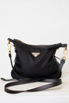 A black Prada nylon shoulder bag with gold-tone hardware and a triangular Prada logo plaque on the front, displayed on a light gray background with its strap draped in front.