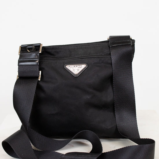 Black Prada bag with a strap on a white background