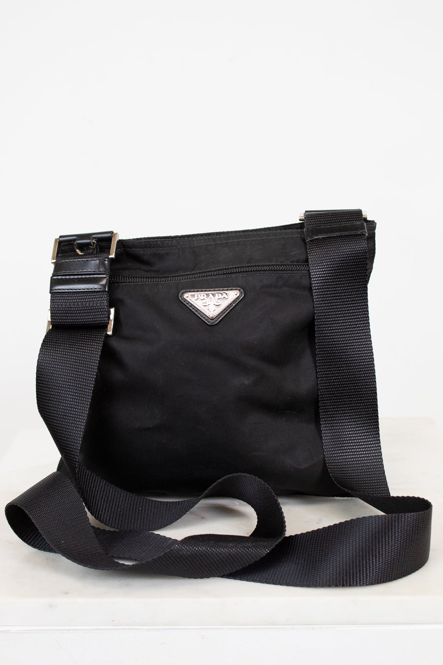 Black Prada bag with a strap on a white background