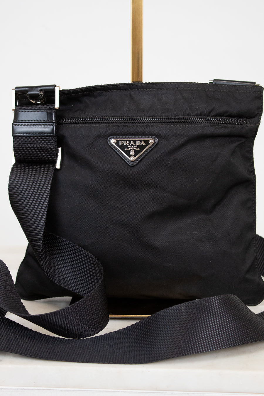 Black Prada bag with a strap on a white background