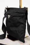 Black crossbody bag with a brand logo on a light background
