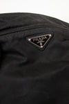 Close-up of a Prada logo on a black nylon fabric bag