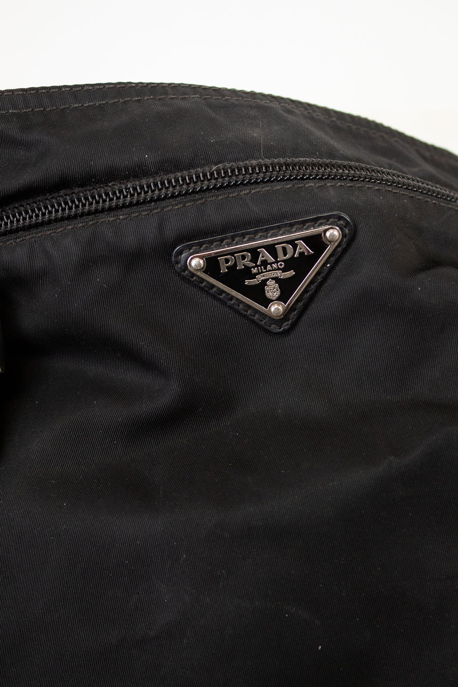Close-up of a Prada logo on a black nylon fabric bag