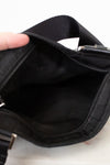 Close-up of a black bag with a hand holding it open on a light background