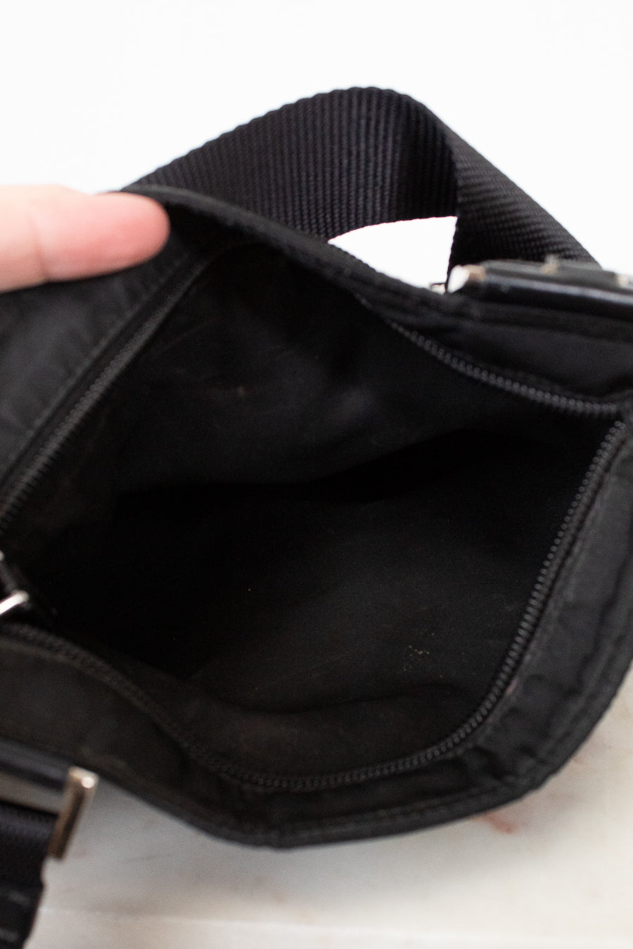 Close-up of a black bag with a hand holding it open on a light background