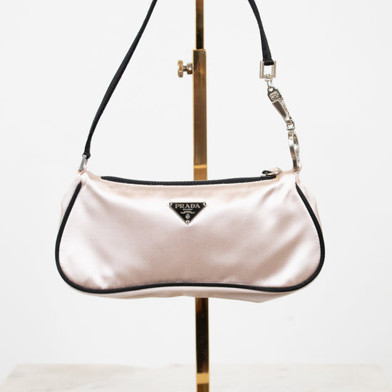 Pink handbag on a gold stand against a white background