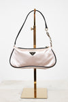 Pink handbag on a gold stand against a white background