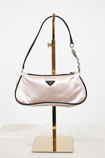 Pink handbag on a gold stand against a white background