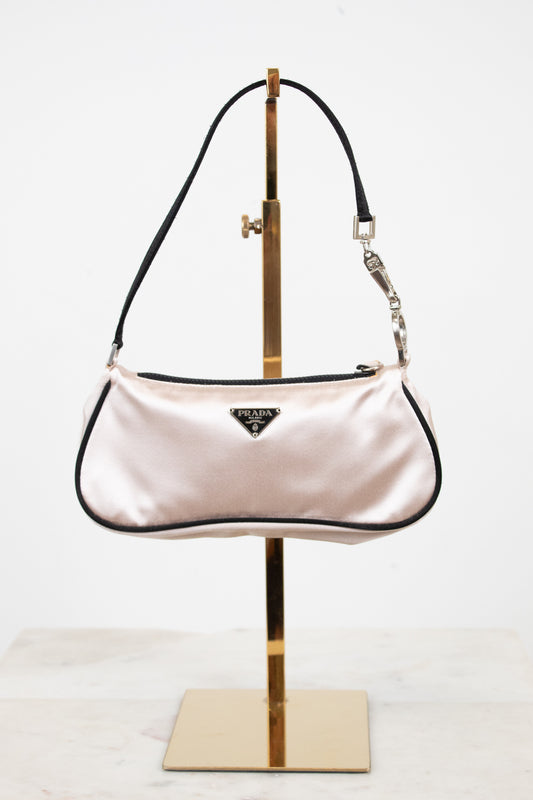 Pink handbag on a gold stand against a white background