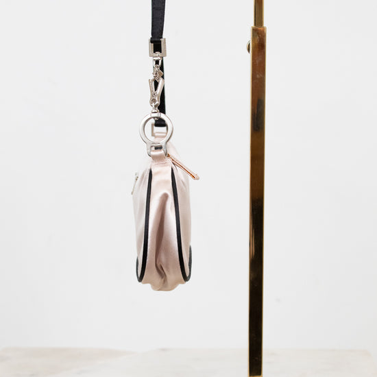 Side profile of small bag with a strap on a gold stand against a white background