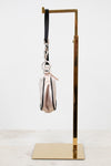 Side profile of small bag with a strap on a gold stand against a white background