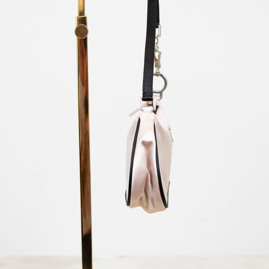 Side view of light pink bag with black strap on a white background