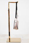 Side view of light pink bag with black strap on a white background