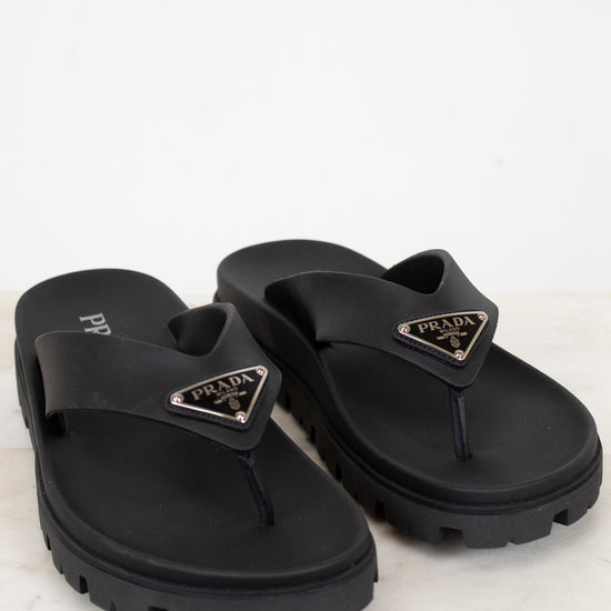Black Prada flip-flops on a light gray background