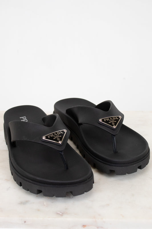 Black Prada flip-flops on a light gray background