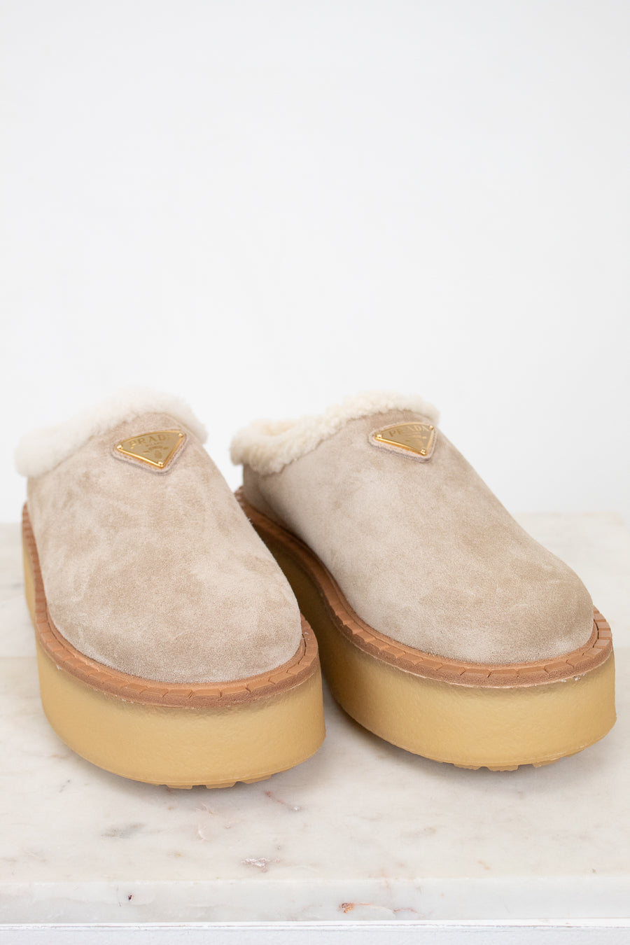 Pair of beige slippers with gum soles on a white background