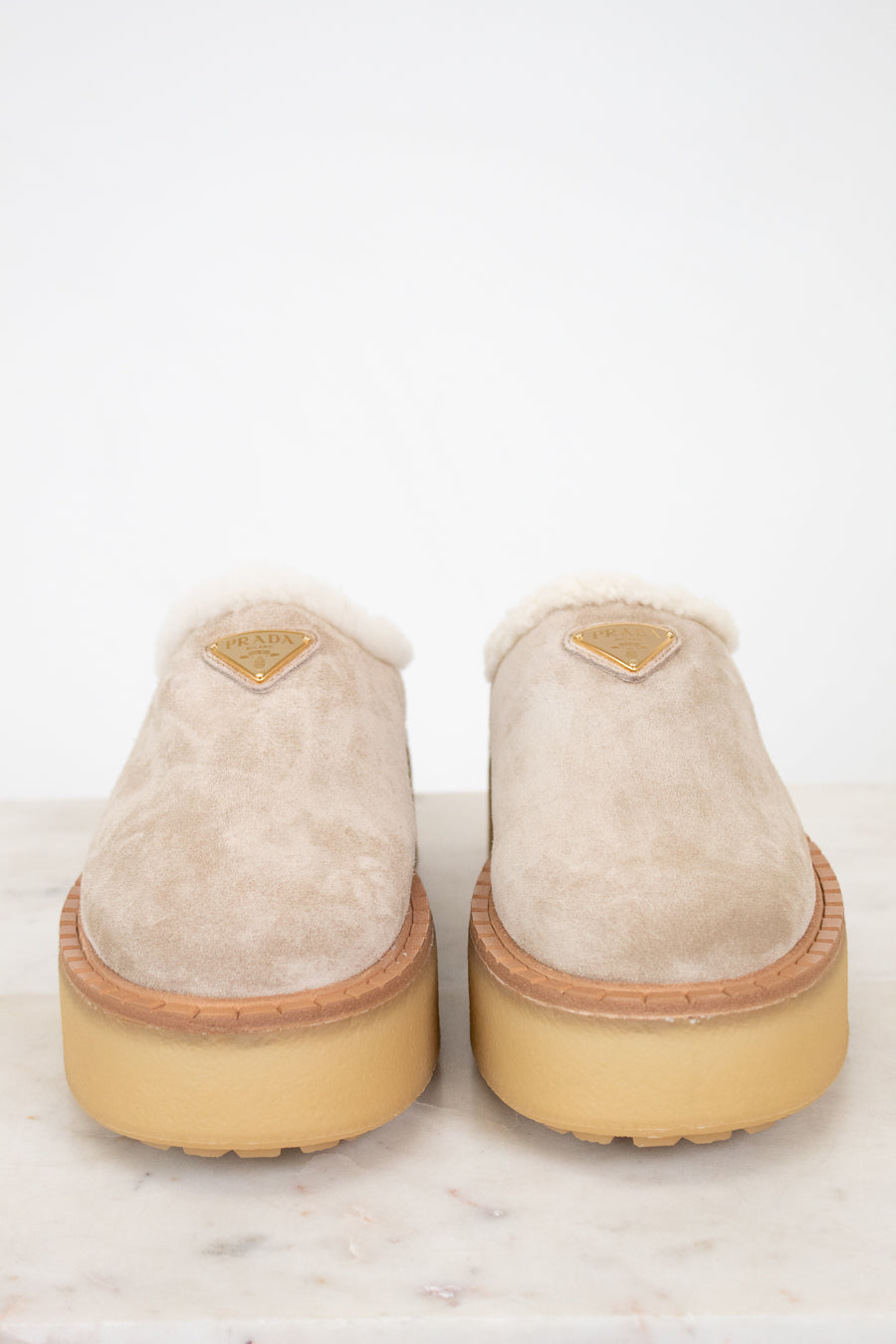 Pair of beige slippers with gum soles on a white background