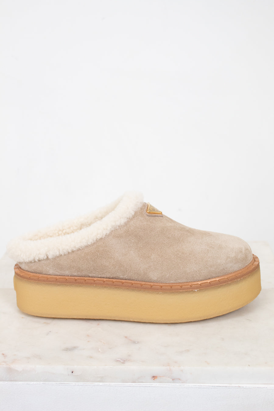 Beige slipper with white shearling lining on a light background