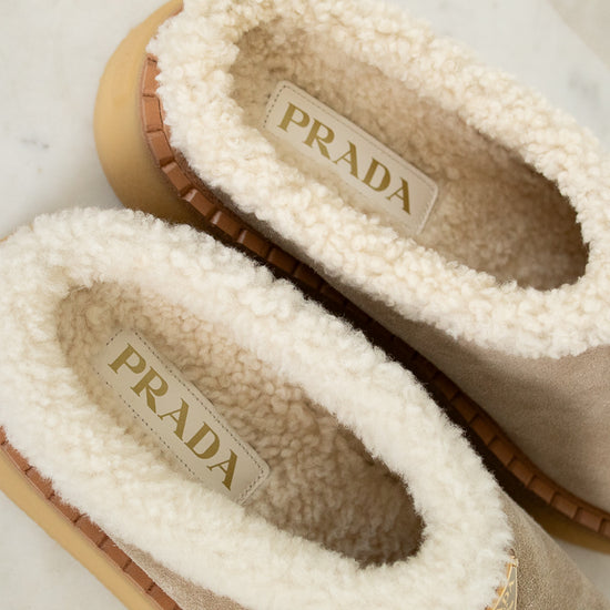 Pair of Prada slippers with shearling interior on a marble surface