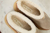 Pair of Prada slippers with shearling interior on a marble surface