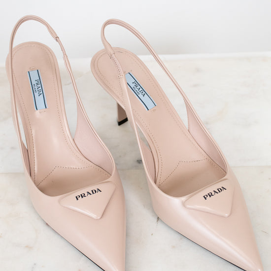 Pair of nude Prada high-heeled shoes on a light background