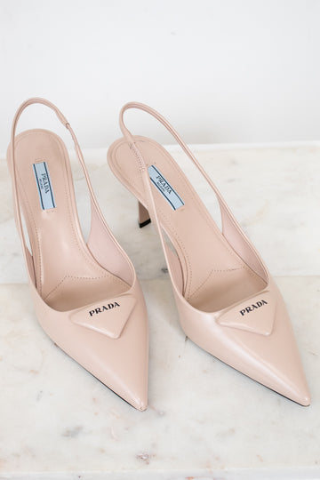 Pair of nude Prada high-heeled shoes on a light background