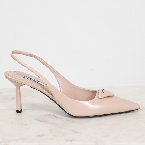 Nude high-heeled shoe on a light marble surface with a white background