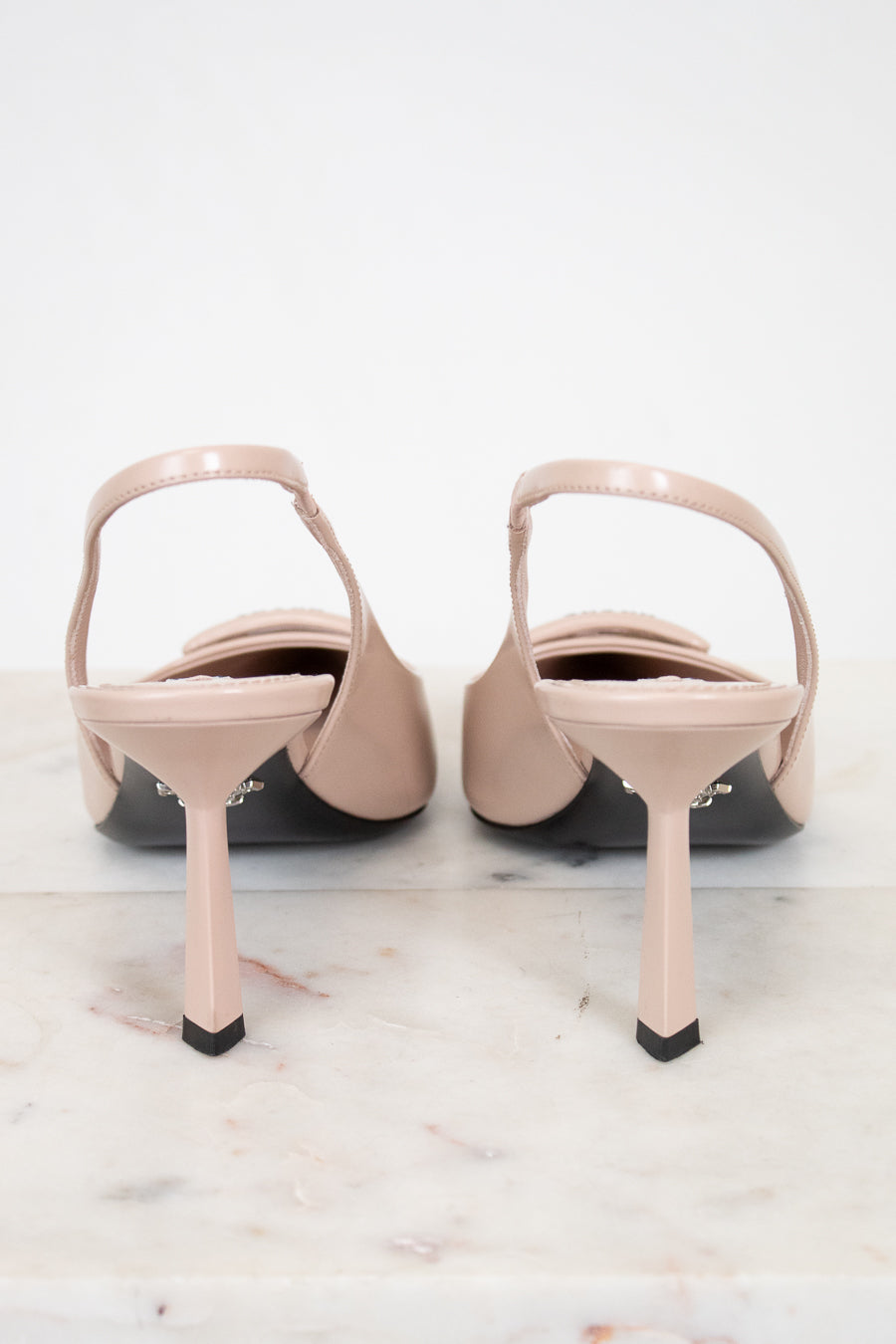 Pair of beige high-heeled shoes on a light marble surface