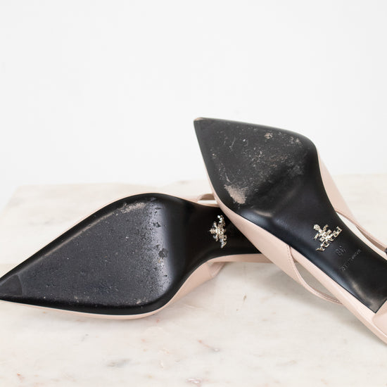 nude high-heeled shoes with black sole with gold accents on a marble surface