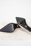 nude high-heeled shoes with black sole with gold accents on a marble surface