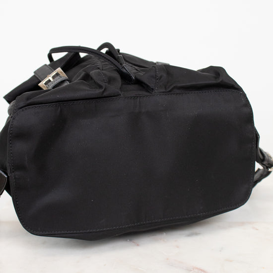 Bottom view of black nylon backpack against a plain background