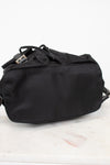 Bottom view of black nylon backpack against a plain background