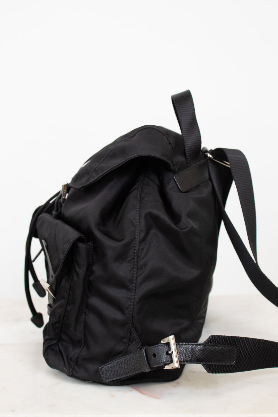Side view of black nylon backpack against a plain background