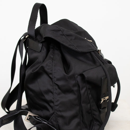 Side view of black nylon backpack against a plain background