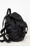 Side view of black nylon backpack against a plain background