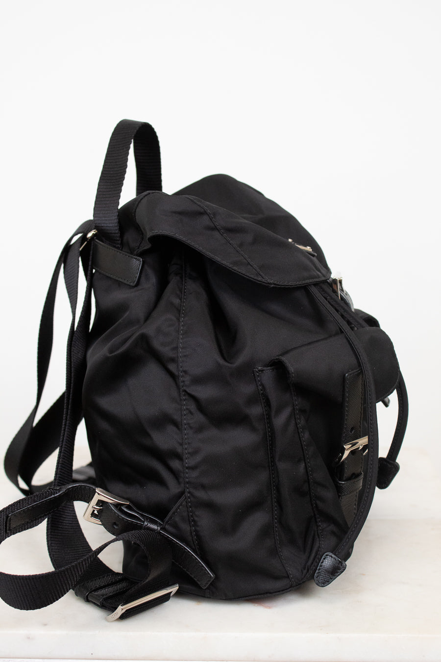 Side view of black nylon backpack against a plain background
