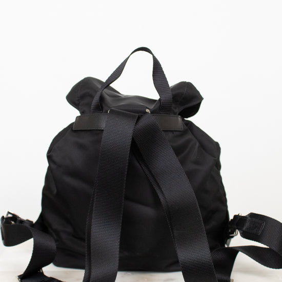 Back view of black nylon backpack showing adjustable straps and top handle displayed against a plain background