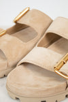 Beige sandals with gold buckles on a light gray background